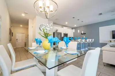 a dining room with a glass table and white chairs at Stunning 5Bd with Pool at Storey Lake 5019 in Kissimmee