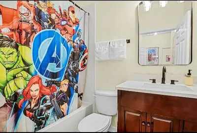 a bathroom with a superhero shower curtain next to a toilet at Disney Paradise-Family Friendly- Near to Disney in Orlando