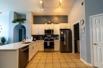 a kitchen with white cabinets and stainless steel appliances at Disney World Vacation Home in Orlando