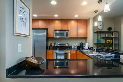 a kitchen with wooden cabinets and a stainless steel refrigerator at Stunning & Luxurious 2Bed 2Bath Open floor plan in Orlando