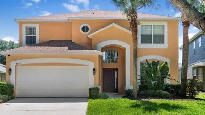 a large orange house with a garage at Lovely 7 Bed Pool Home with Game Room-8510PHD home in Kissimmee