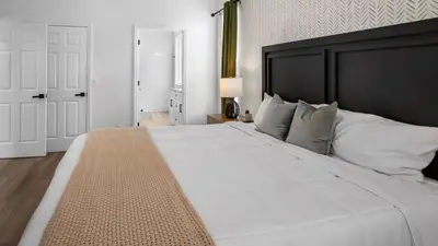 a bedroom with a large white bed with a black headboard at Lovely 7 Bed Pool Home with Game Room-8510PHD home in Kissimmee