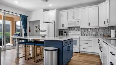 a kitchen with white cabinets and a blue island at Lovely 7 Bed Pool Home with Game Room-8510PHD home in Kissimmee