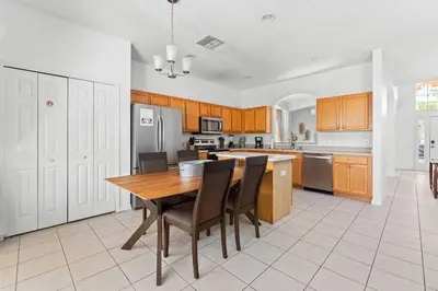 a large kitchen with a wooden table and chairs at 7BR Family Friendly Resort Pool Home Near Disney World in Kissimmee
