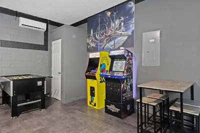 a room with a video game machine and a table at 7BR Family Friendly Resort Pool Home Near Disney World in Kissimmee