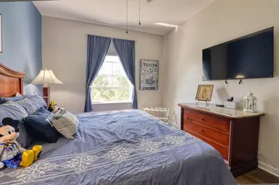 a bedroom with a bed with a tv on the wall at Amazing Condo in Windsor Hills Close to Disney in Orlando
