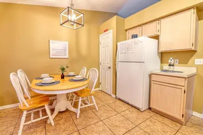 a kitchen with a table and a white refrigerator at 9 Miles to Disney - Family Friendly - Private Pool in Orlando