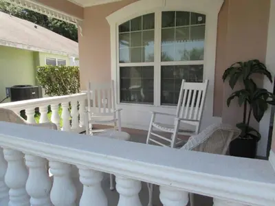 a porch with white chairs and a white railing at Creekside Kissimmee in Kissimmee