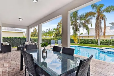 an indoor patio with a glass table and chairs next to a swimming pool at Magic Manor in Orlando