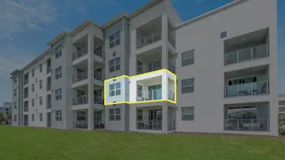 a white apartment building with a yellow balcony at WaterLily at Storey Lake in Orlando
