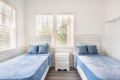 two beds in a room with two windows at LUXURY 6000 sqft Mansion in Downtown Orlando Sleeps 12 in Orlando