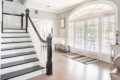 a staircase in a living room with a large window at LUXURY 6000 sqft Mansion in Downtown Orlando Sleeps 12 in Orlando