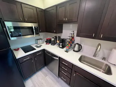 a kitchen with brown cabinets and a sink and a microwave at DisneyShuttleKing & Queen Be 5 minutes to Disney in Orlando