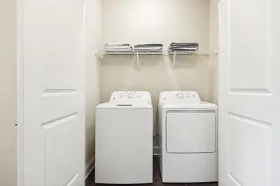 a white laundry room with two washer and dryer at The Edge at Millenia in Orlando