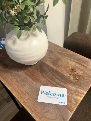 a white vase on a wooden table with a welcome sign at Renovated and cozy apartment near universal in Orlando