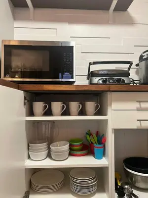 a kitchen with a microwave and some plates and cups at Renovated and cozy apartment near universal in Orlando