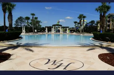 a large swimming pool in a park with palm trees at Beautiful 3 bed townhome in Windsor Hills Resort townhouse in Orlando
