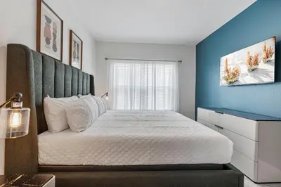 a bedroom with a large bed with a blue wall at Brand New 5BedroomsPool LED At Paradiso Grande in Orlando