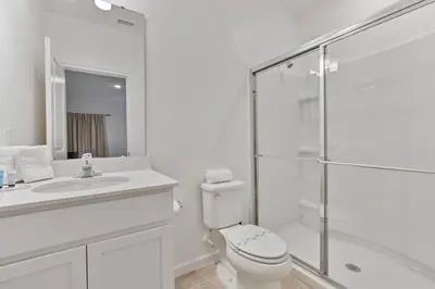 a white bathroom with a toilet and a glass shower at Cozy New 5Bedrooms At Paradiso Grande in Orlando