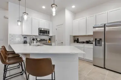 a kitchen with white cabinets and a stainless steel refrigerator at Cozy New 5Bedrooms At Paradiso Grande in Orlando