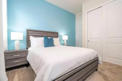 a bedroom with a large bed with blue walls at 2024 Coastal Villa 3 suites near Disney in Orlando