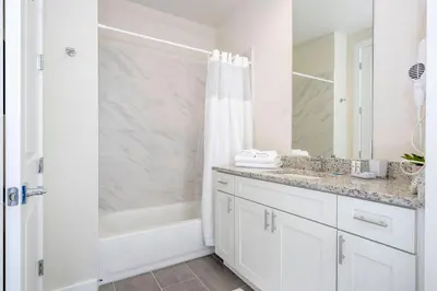 a white bathroom with a shower and a sink at 2024 Coastal Villa 3 suites near Disney in Orlando