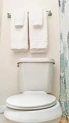 a bathroom with a toilet with towels hanging on the wall at Vacation Family Home - Close to Disney in Kissimmee