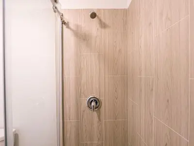 a shower with a wooden wall and a shower door at Orlando Paradise 1BR With view & minutes to Disney in Kissimmee