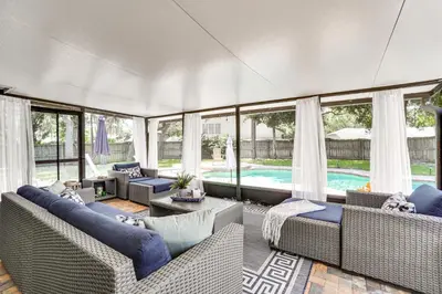 a living room with wicker furniture and a pool at Screened Lanai and Fenced Yard Luxe Orlando Home in Orlando