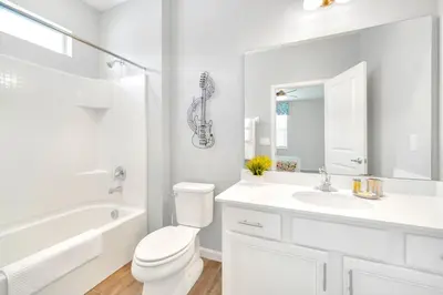 a white bathroom with a toilet and a sink at Upstay Sleeps 26 w Private Pool, Hot Tub, Games in Kissimmee