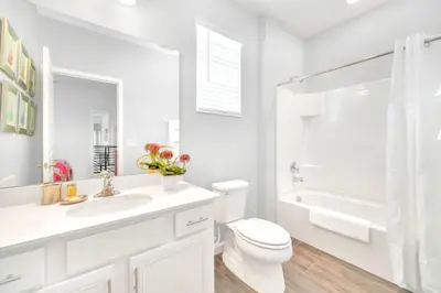 a white bathroom with a toilet and a sink at Upstay Sleeps 26 w Private Pool, Hot Tub, Games in Kissimmee