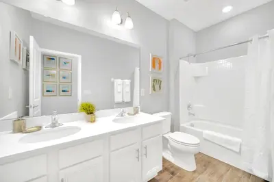 a white bathroom with two sinks and a toilet at Upstay Sleeps 26 w Private Pool, Hot Tub, Games in Kissimmee