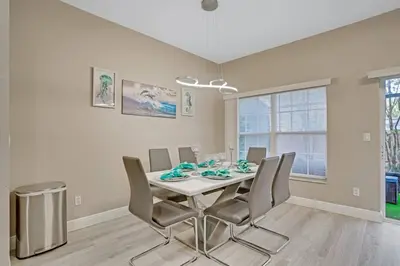 a dining room with a white table and chairs at Modern 4 BR Townhouse near Disney in Kissimmee
