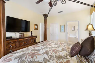 a bedroom with a large bed and a flat screen tv at Private Pool, Spa, Game Room & Theme Park Magic in Kissimmee