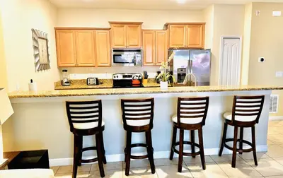 a kitchen with a counter with four bar stools at Orlando Area Vacation Rental with private pool in Kissimmee