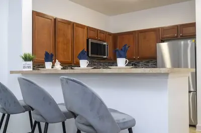 a kitchen with four chairs and a counter with a refrigerator at A Magical condo close to Disney CSS1 in Kissimmee