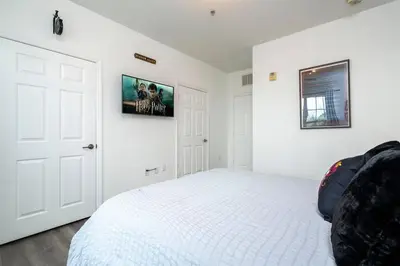a white bedroom with a bed and a picture on the wall at A Magical condo close to Disney CSS1 in Kissimmee