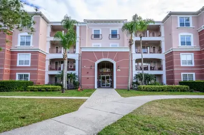 a pink building with palm trees in front of it at Luxury Lakeview, Vista Cay Orlando 1027 in Orlando