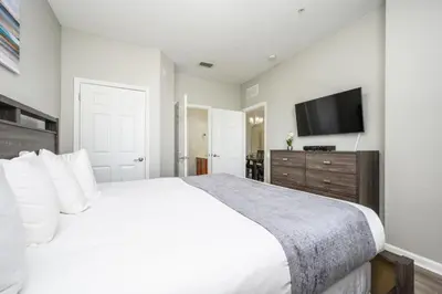 a bedroom with a white bed and a flat screen tv at Epic Universe New Listing Beautiful Vacation Condo - 3018 in Orlando