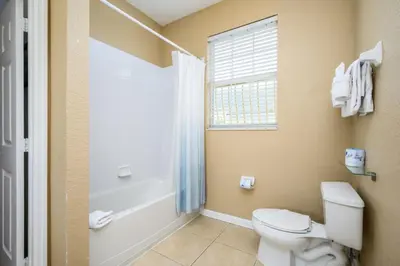 a bathroom with a toilet and a tub and a window at Beautiful Modern Condo, Near The Parks! 3021 in Orlando
