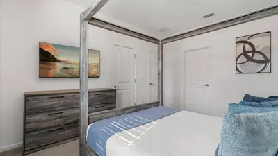a bedroom with a canopy bed and white walls at Upstay Family Home w Pool, Cinema & Games Room in Kissimmee