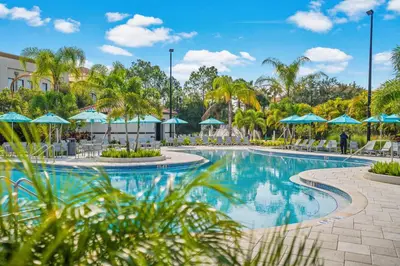 a swimming pool at a resort with blue umbrellas at Brand New Modern Vista Cay Reserve Condo - 5003 in Orlando