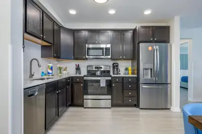 a kitchen with wooden cabinets and stainless steel appliances at Epic Universe Brand New Modern Vista Cay Reserve Condo - 6005 in Orlando