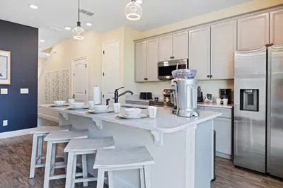 a kitchen with white cabinets and a large island with stools at 3148 Caribbean Soul Drive in Orlando