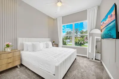 a white bedroom with a large bed and a window at 5 BD 5BA Themed House Near Disney in Orlando