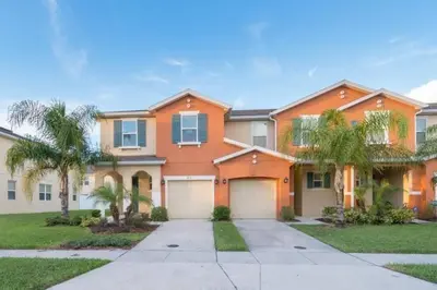 a large orange house with palm trees in front of it at Pool Private tub BBQ Mins to Disney and Universal in Kissimmee