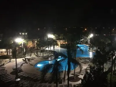 a large pool with palm trees and lights at night at POOL VIEW 3 Bedroom Condo at Windsor Hills 'The Lido Deck' in Orlando