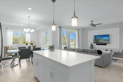 a white kitchen and living room with a white island at 2 Bedrooms 2 Bathrooms Storey Lake Ct in Kissimmee