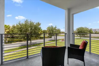 two chairs on a balcony with a view of a field at 2 Bedrooms 2 Bathrooms Storey Lake Ct in Kissimmee