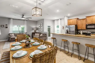 a kitchen and living room with a table and chairs at Palms of Paradise! in Kissimmee